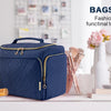 A navy blue bagsmart toiletry bag with a handle sits on a white surface next to various grooming tools and flowers.