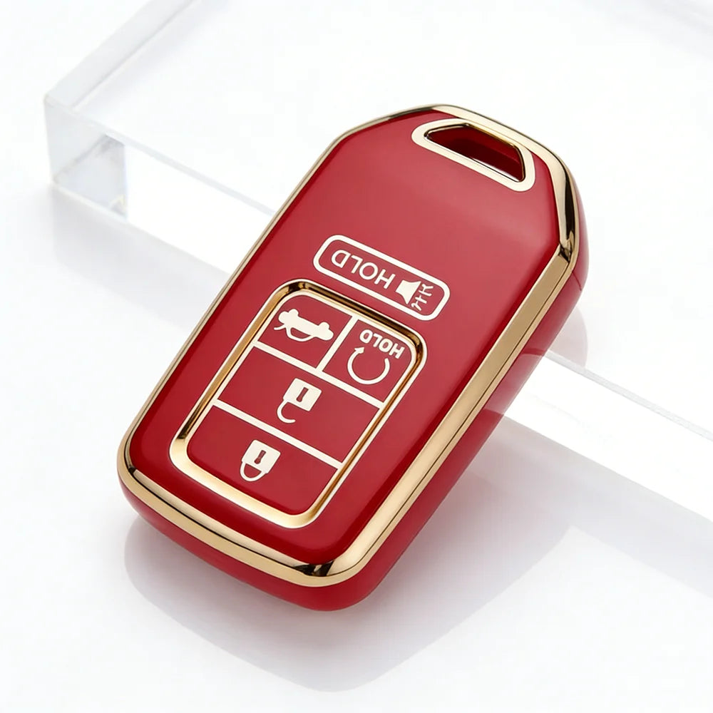 A red TPU protective key case with gold accents is shown resting on a clear glass surface.