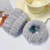 A pair of gray microfiber wrist sweatbands and scrunchies are displayed next to a yellow bowl.