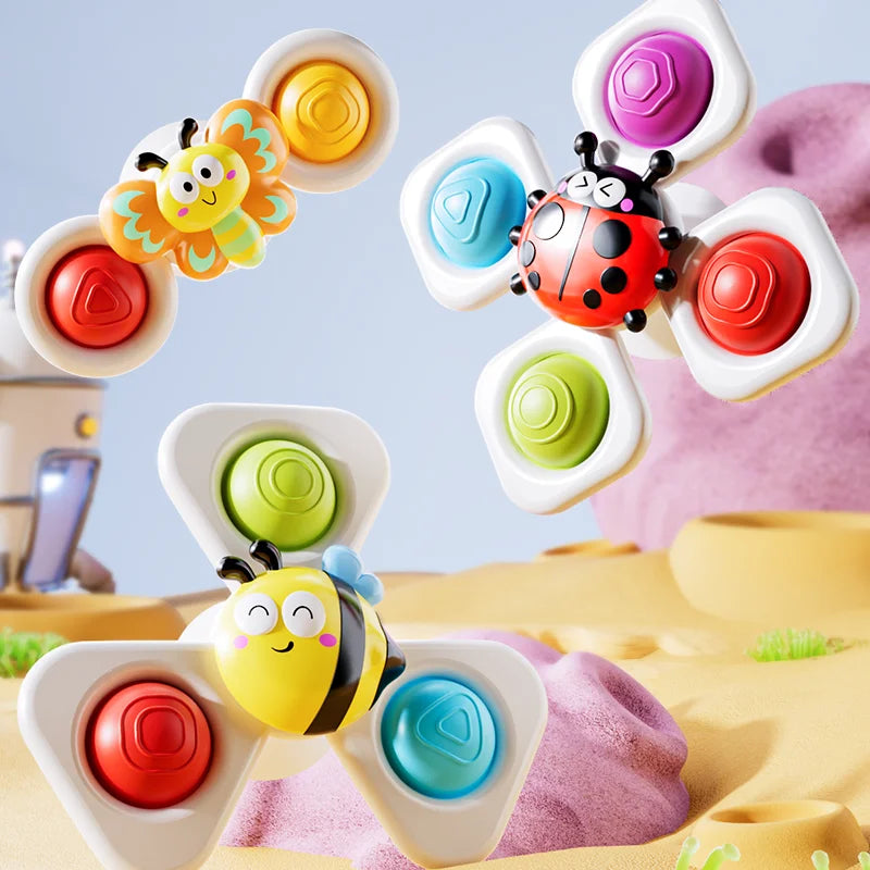 A set of colorful, ocean-themed spinning bath toys featuring bees and flowers on a soft fabric background.