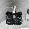 A black ceramic pump dispenser with a silver pump mechanism sits on a gray stone surface.
