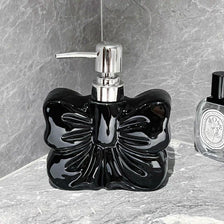 A black ceramic pump dispenser with a silver pump mechanism sits on a gray stone surface.