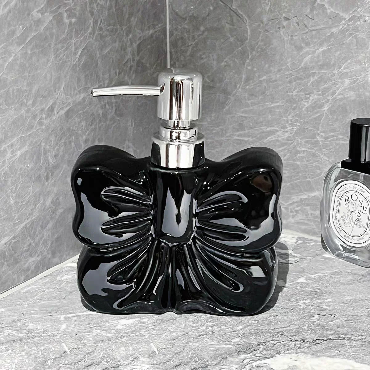 A black ceramic pump dispenser with a silver pump mechanism sits on a gray stone surface.