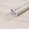 Two rolls of self-adhesive wood grain waterproof wallpaper lying on a light wooden surface.