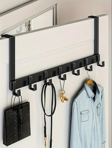 A black over-the-door coat rack with six hooks mounted on a white wall for extra storage.
