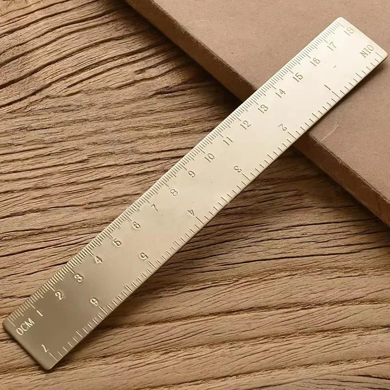 Messlatte in Form eines goldenen Dreiecks diagonal auf einer Holzoberfläche.