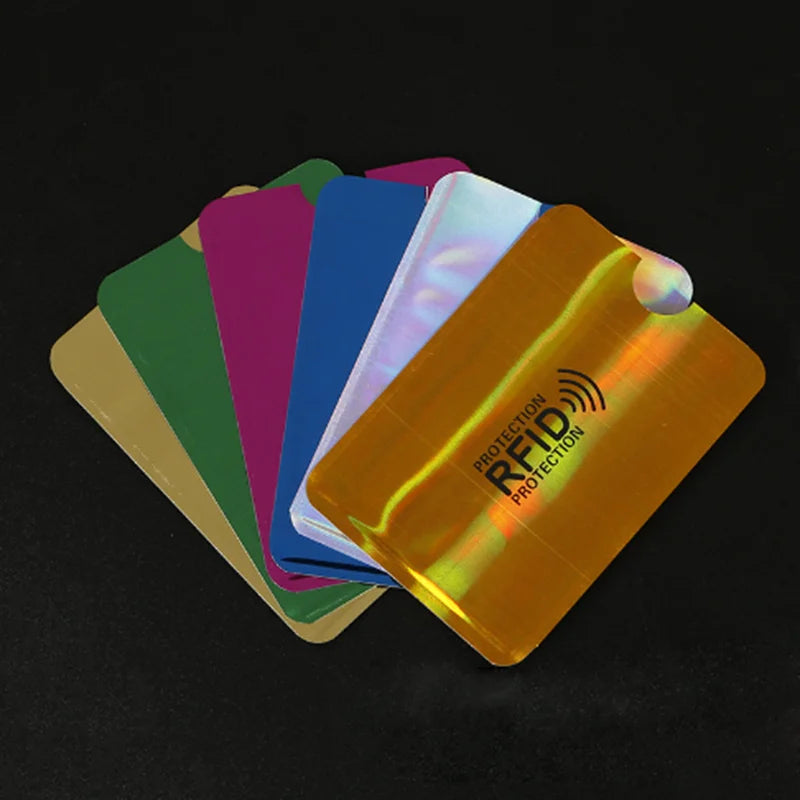 A stack of colorful RFID blocking aluminum cards, including green, purple, blue, and orange, are displayed on a dark surface.