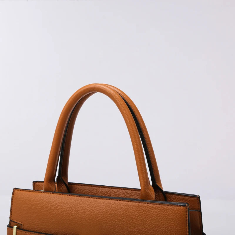 A brown leather handbag with a curved handle and matching coin purse against a light background.