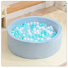 A light blue plastic ball pit filled with clear and white plastic balls on a wooden floor.