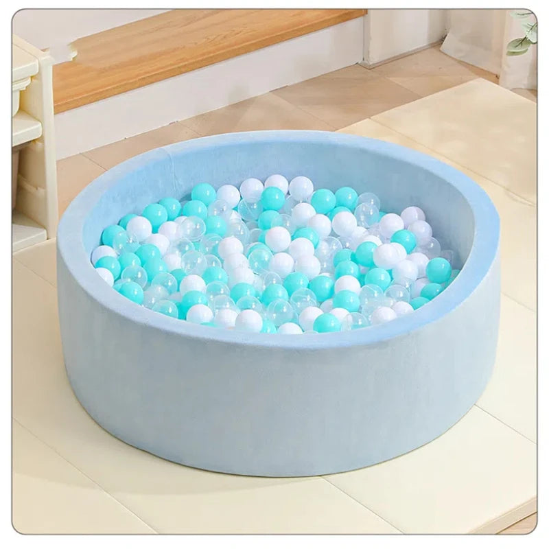 A light blue plastic ball pit filled with clear and white plastic balls on a wooden floor.