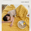 A yellow taffeta multifunctional blanket is draped over a person relaxing on a light-colored surface.