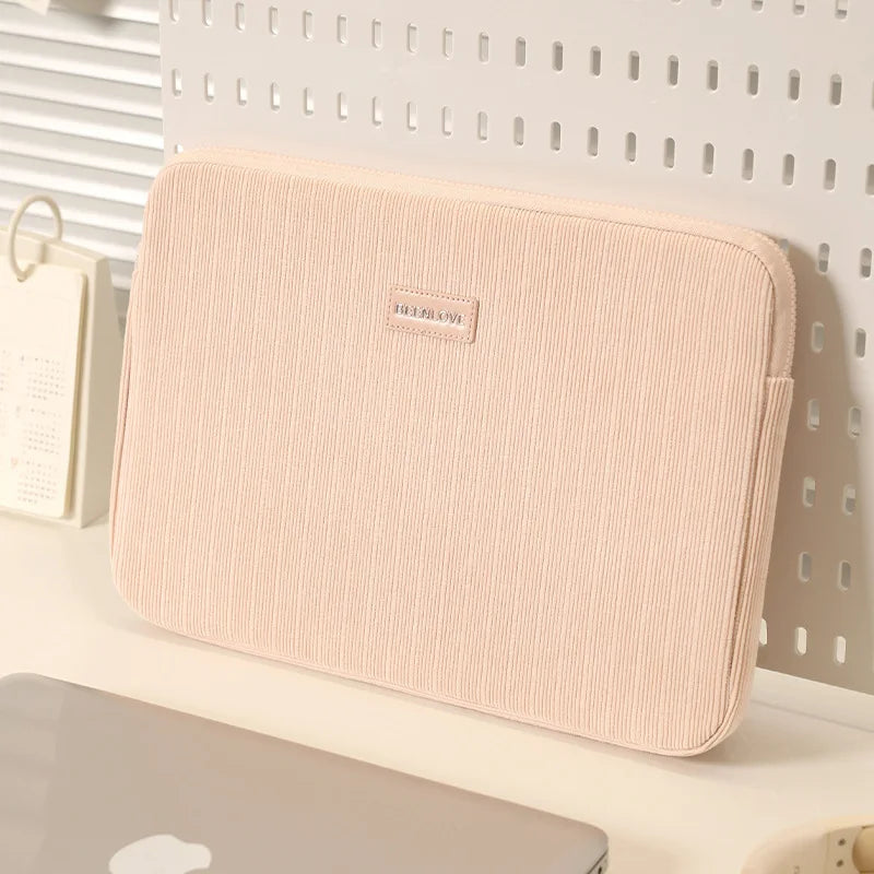 Una funda protectora beige para laptop mostrada contra un fondo blanco.