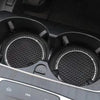 A close-up view of a black crystal rhinestone non-slip cup mat for cars inside a vehicle console.