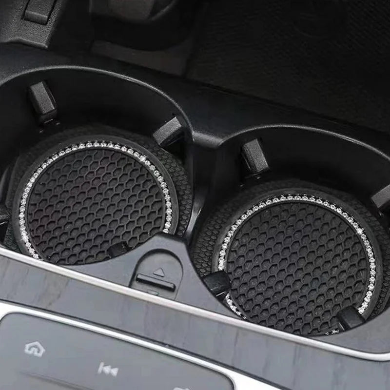 A close-up view of a black crystal rhinestone non-slip cup mat for cars inside a vehicle console.