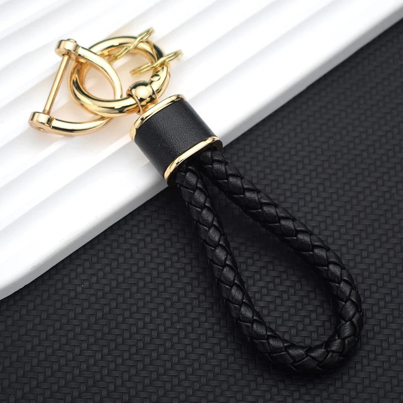 A gold-colored keychain featuring a black leather cord and a durable TPU car key fob cover.