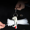 A hand holds a spool of white fluorescent cable ties for cord management, with a metal clip attached.