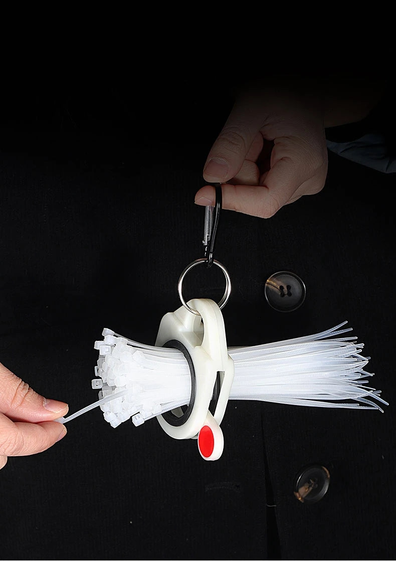 A hand holds a spool of white fluorescent cable ties for cord management, with a metal clip attached.