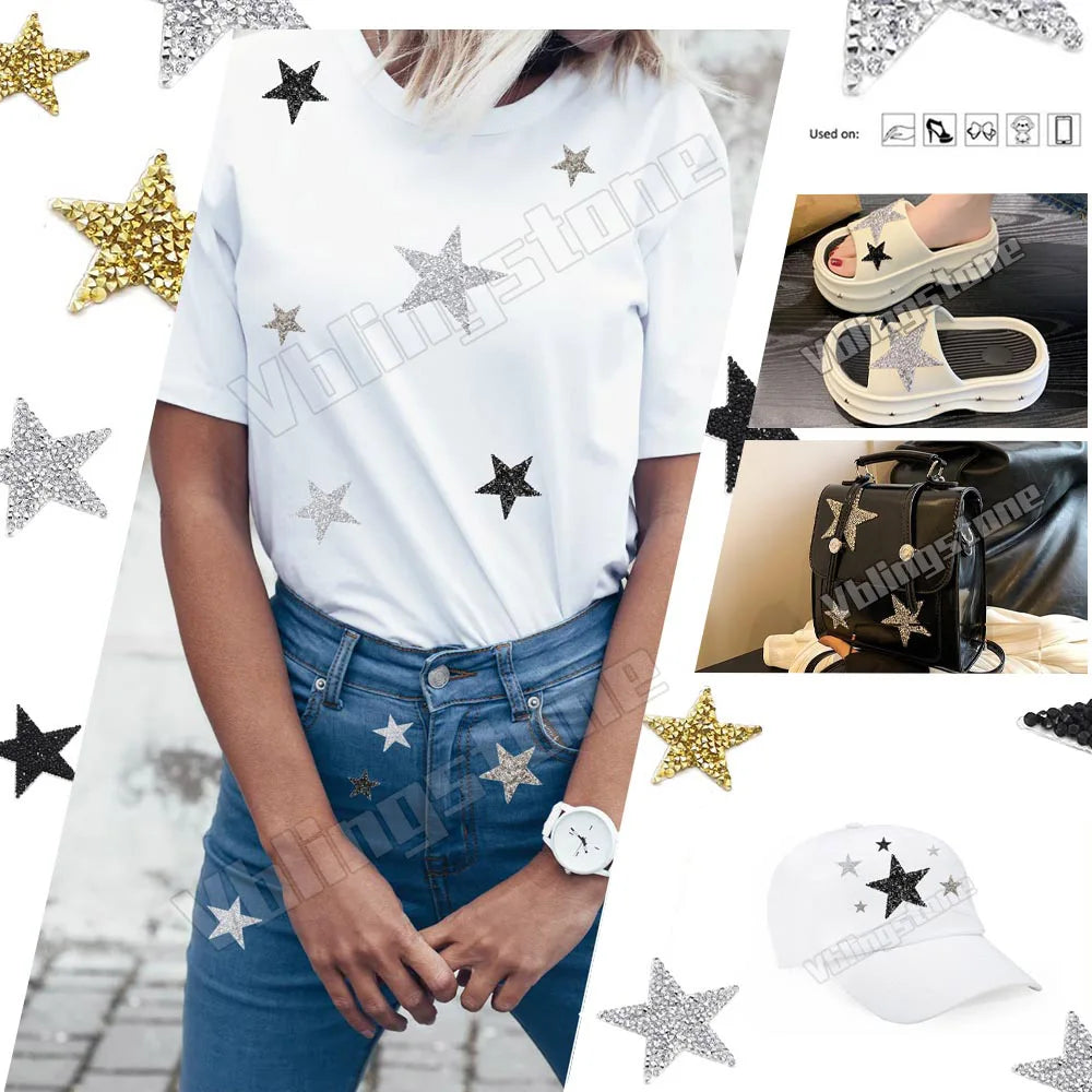 A white t-shirt featuring silver and gold rhinestone star patches, displayed on a model wearing blue jeans.