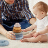 A baby is interacting with a stack of soft silicone building blocks on a light surface.
