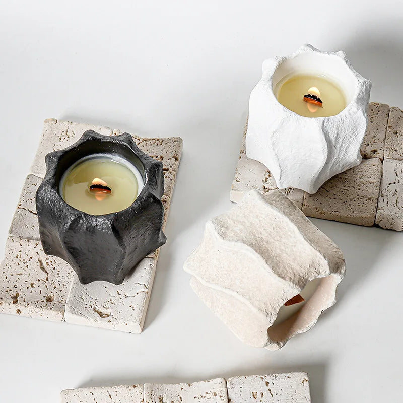 White plaster decor candle holders and molds with wavy edges, some holding candles.
