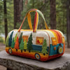 A quilted travel duffle bag featuring colorful stitching and miniature evergreen trees on a wooden surface.