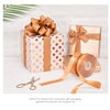 A stack of gold and white polka dot gift boxes tied with satin ribbon rolls for fashion accessories