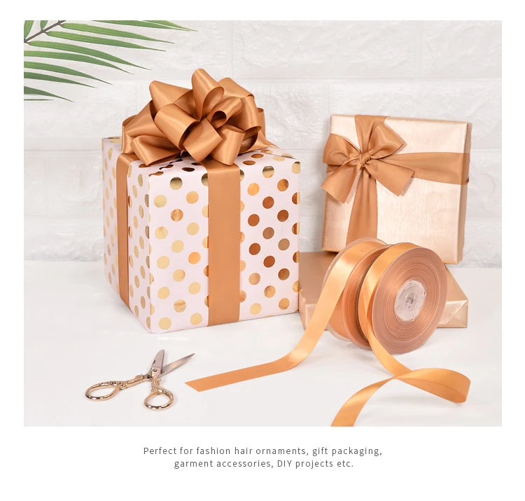 A stack of gold and white polka dot gift boxes tied with satin ribbon rolls for fashion accessories