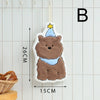 A fluffy brown cartoon bear hanging accessory with a yellow star on a white towel, displayed against a light tiled background