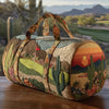A quilted travel duffle bag featuring a desert landscape design with 3D stitching, resting on a wooden surface.