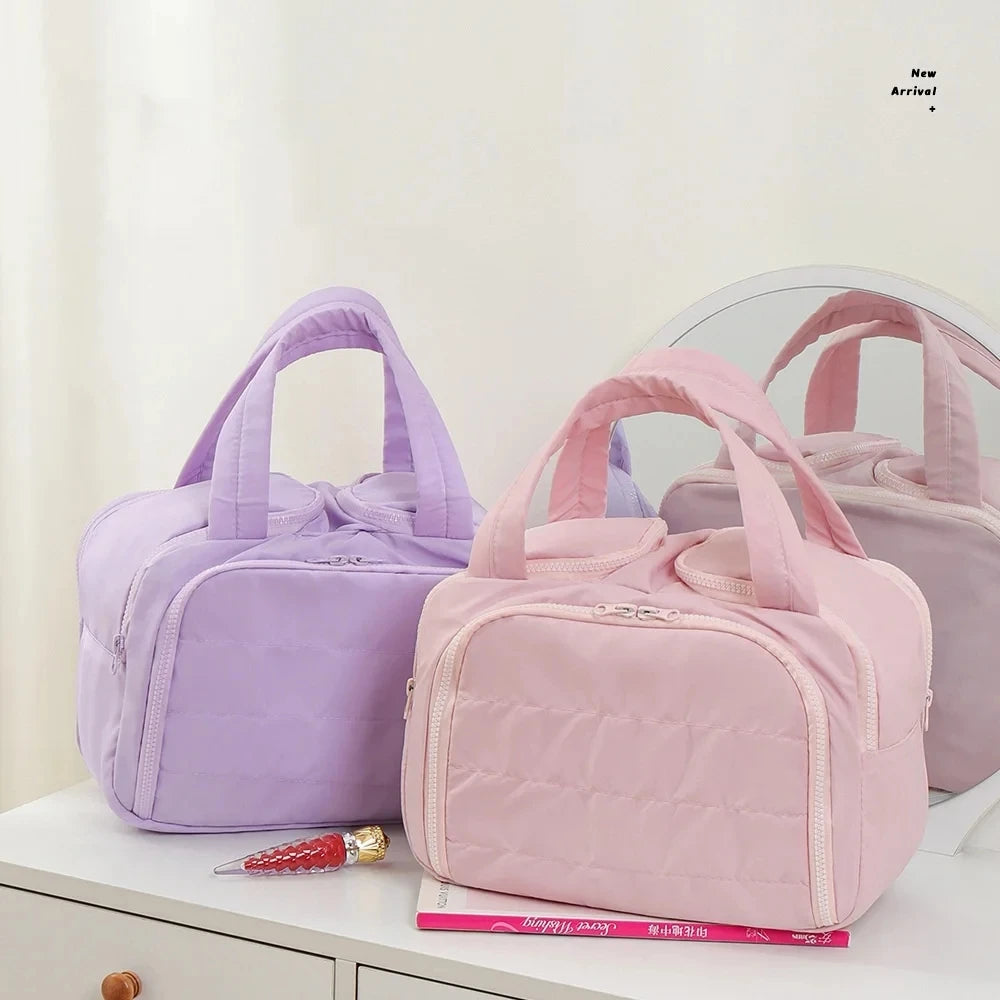 A pink quilted travel makeup bag with a purple bow is displayed on a white surface.