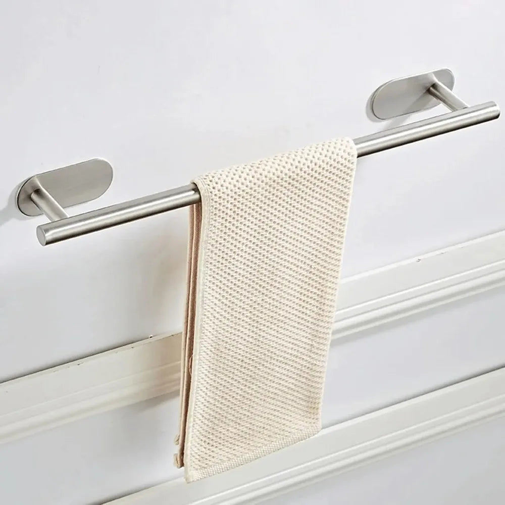 A stainless steel towel holder with a beige textured towel hanging on a white wall.