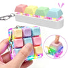A hand holds a colorful LED macaron keyboard fidget toy with attached keychains and light-up features.