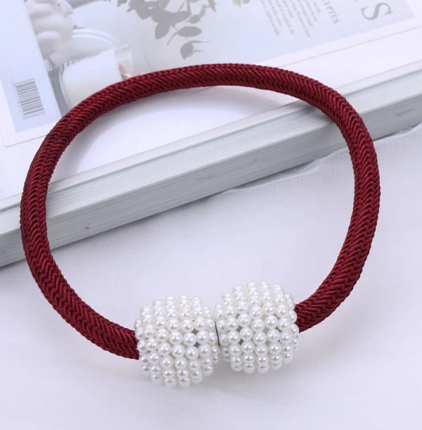 A maroon cord bracelet with two clusters of white pearls displayed on a white background.