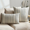 A set of two beige and gray bohemian linen pillow covers displayed on a light-colored sofa.