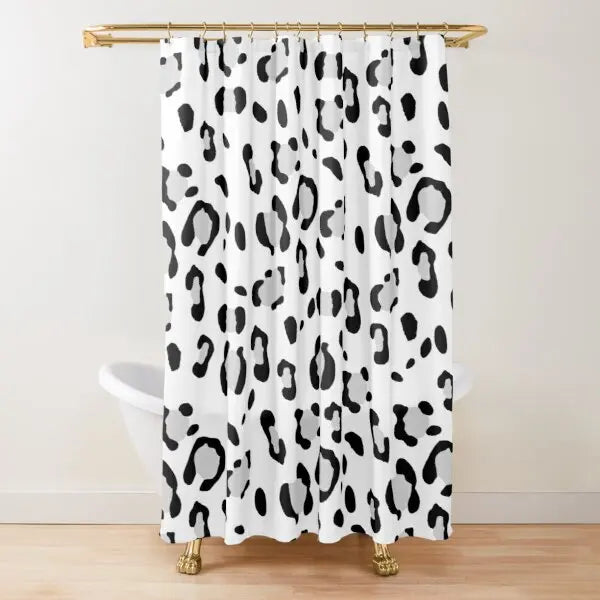 A white shower curtain featuring a black and gray leopard print pattern hanging from a gold rod.
