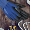 A dark blue and black work glove is shown on a wooden surface next to various tools.