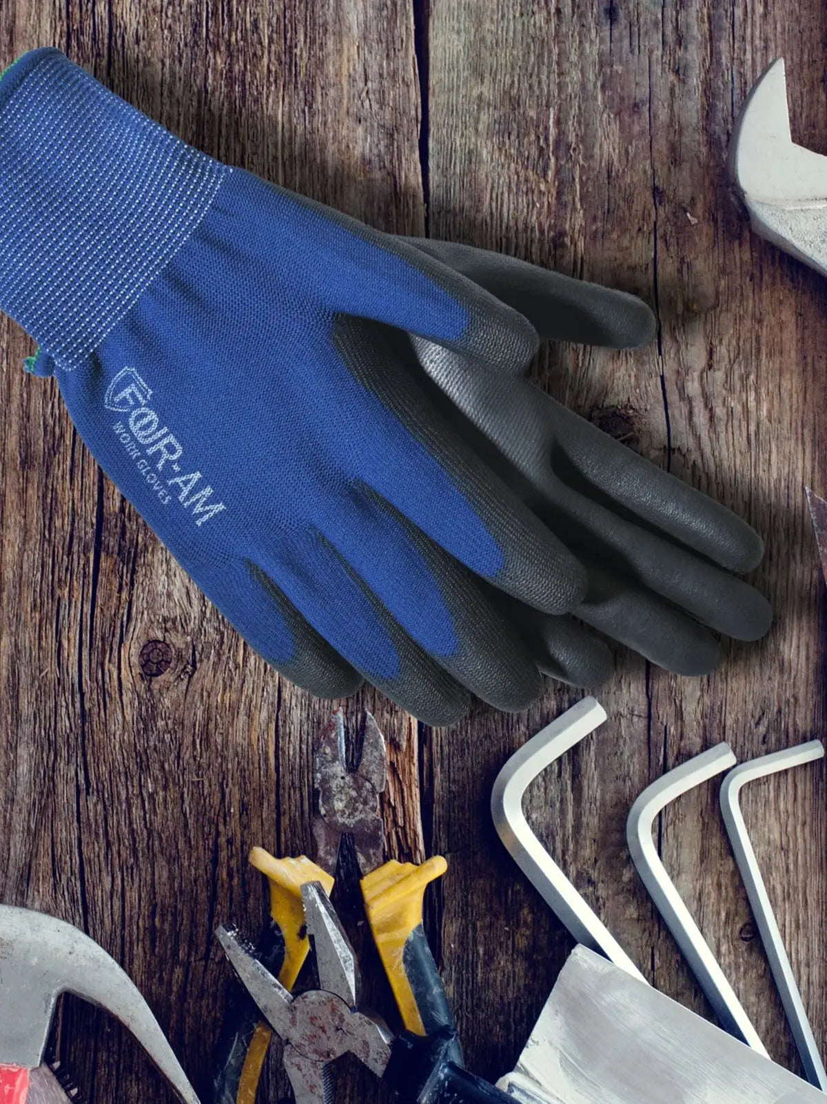A dark blue and black work glove is shown on a wooden surface next to various tools.