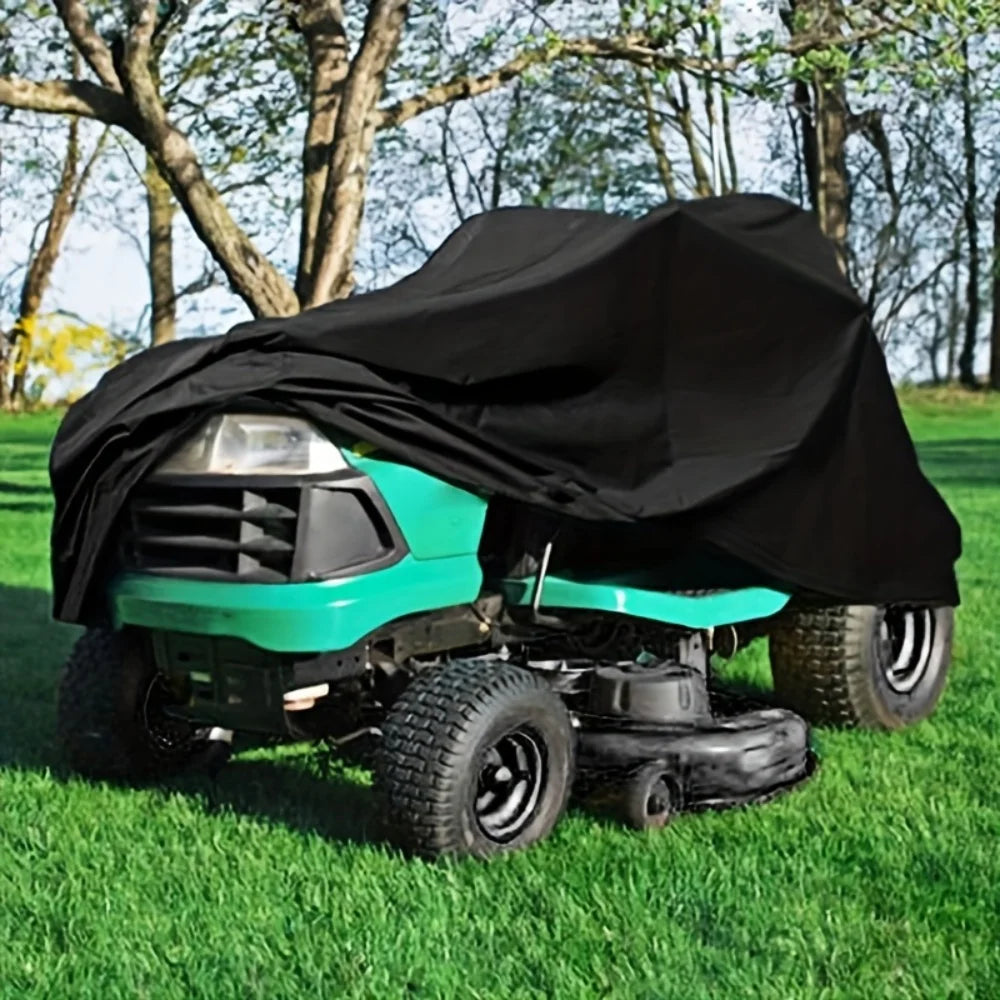 A teal heavy-duty yard tractor is shown with a black waterproof cover placed over it in a grassy field.
