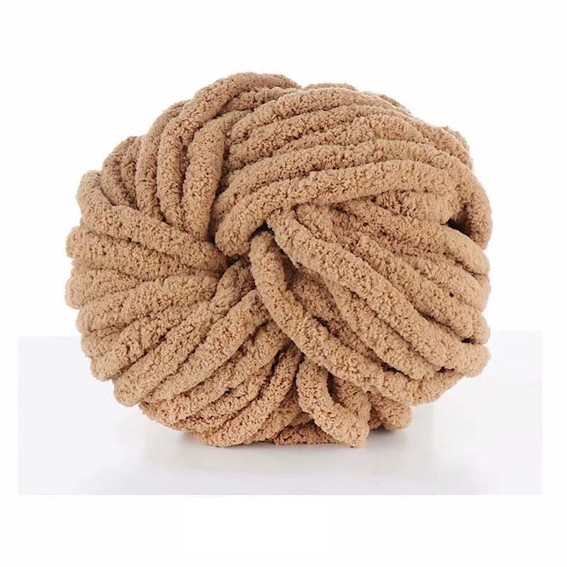 A ball of chunky acrylic yarn in a light tan or beige color for knitting and crochet
