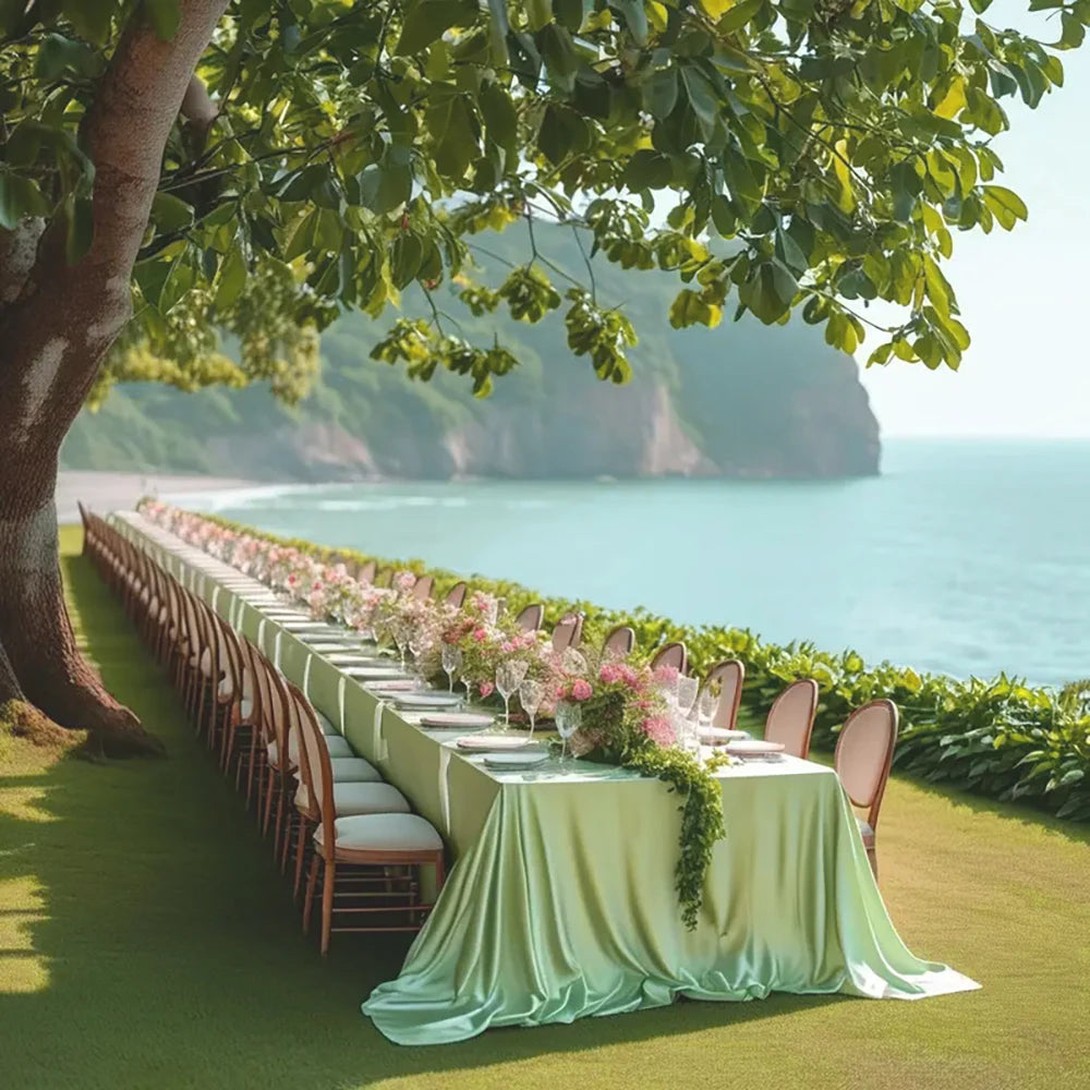 An elegant long table set up outdoors with pink floral decorations overlooking the ocean.
