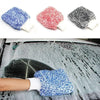 A hand is using a blue microfiber car wash mitt on a wet car surface for detailing.