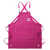 A bright pink cotton canvas apron with cross-back straps and multiple pockets.