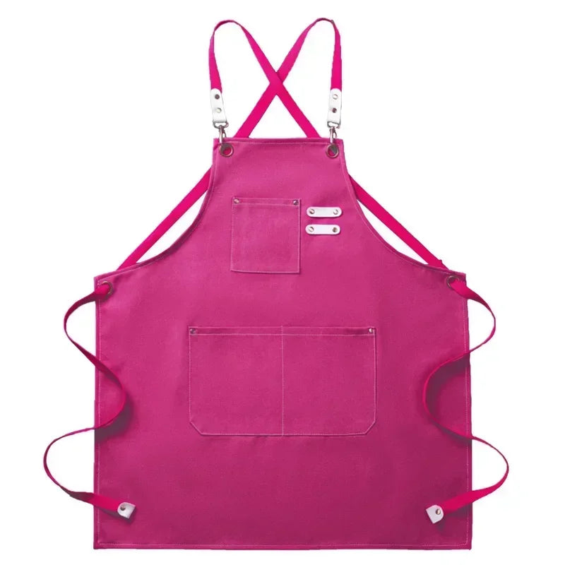 A bright pink cotton canvas apron with cross-back straps and multiple pockets.