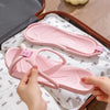 A pair of pink foldable EVA travel slippers being held by a person on a white cloth.