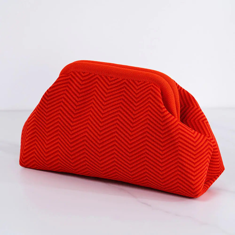 Pochette en crochet orange rayé pliée sur une surface blanche.