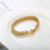 A chunky gold stainless steel link chain bracelet displayed on a white plate.