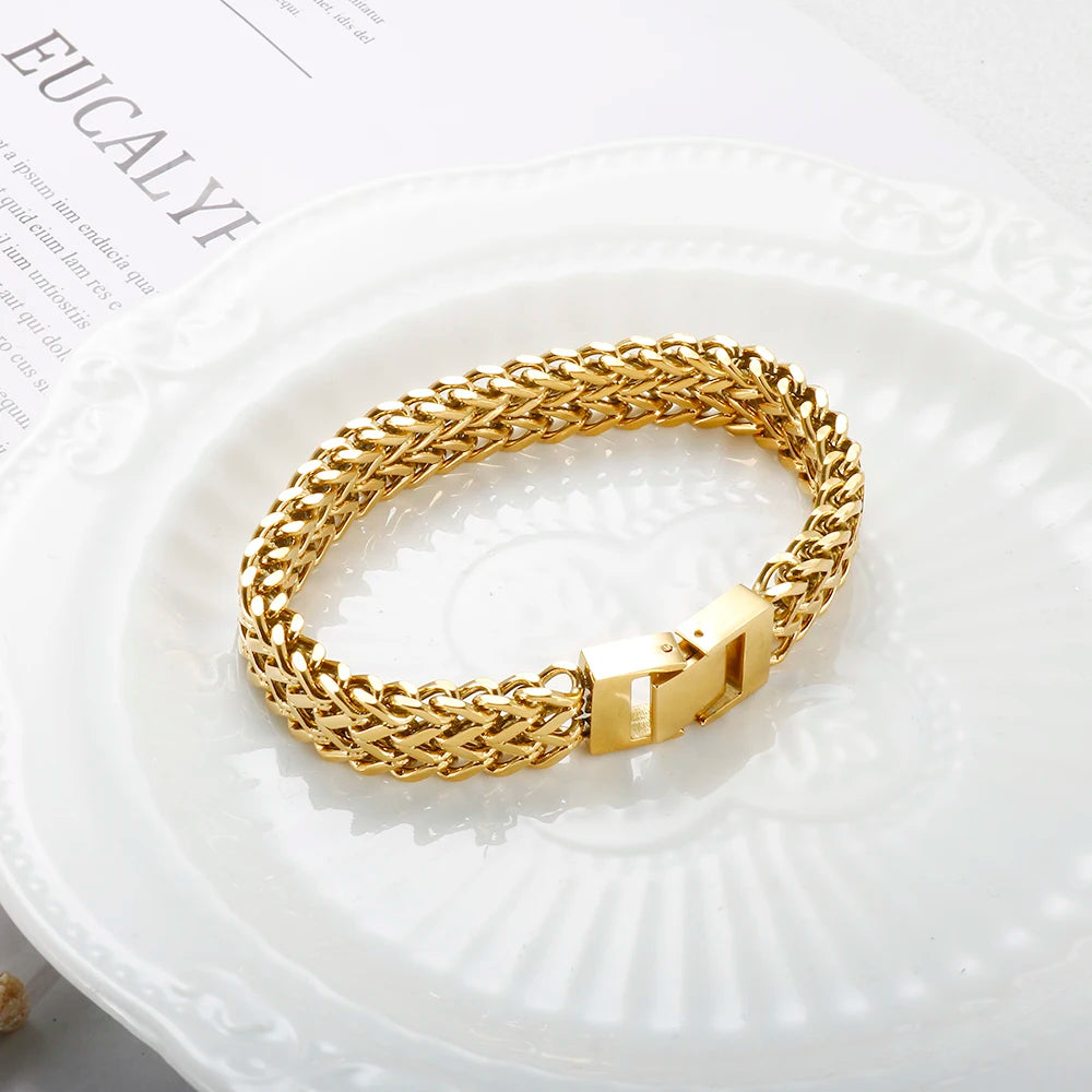A chunky gold stainless steel link chain bracelet displayed on a white plate.