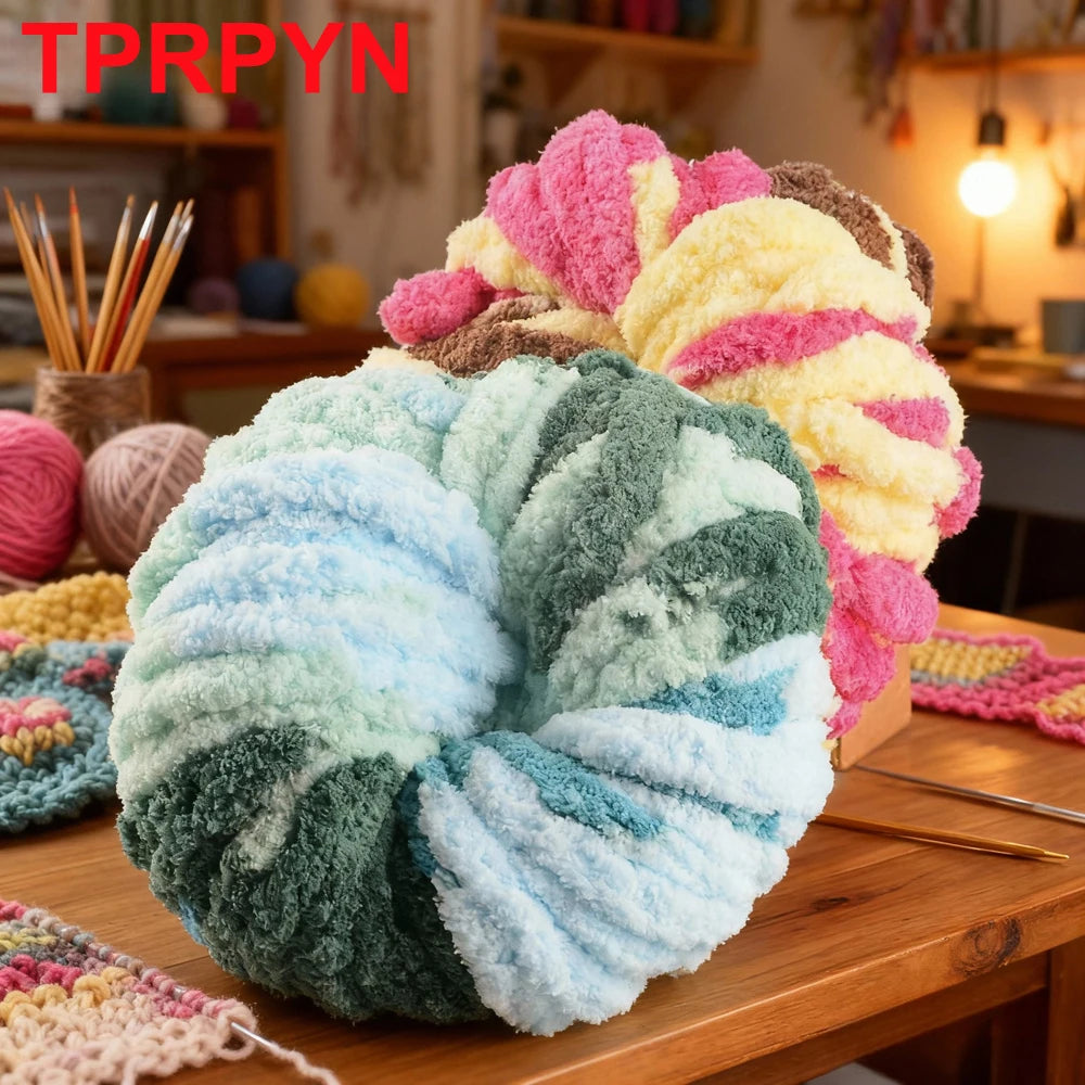 A large ball of fluffy, multicolored chenille yarn used for knitting and crochet is displayed on a wooden surface.