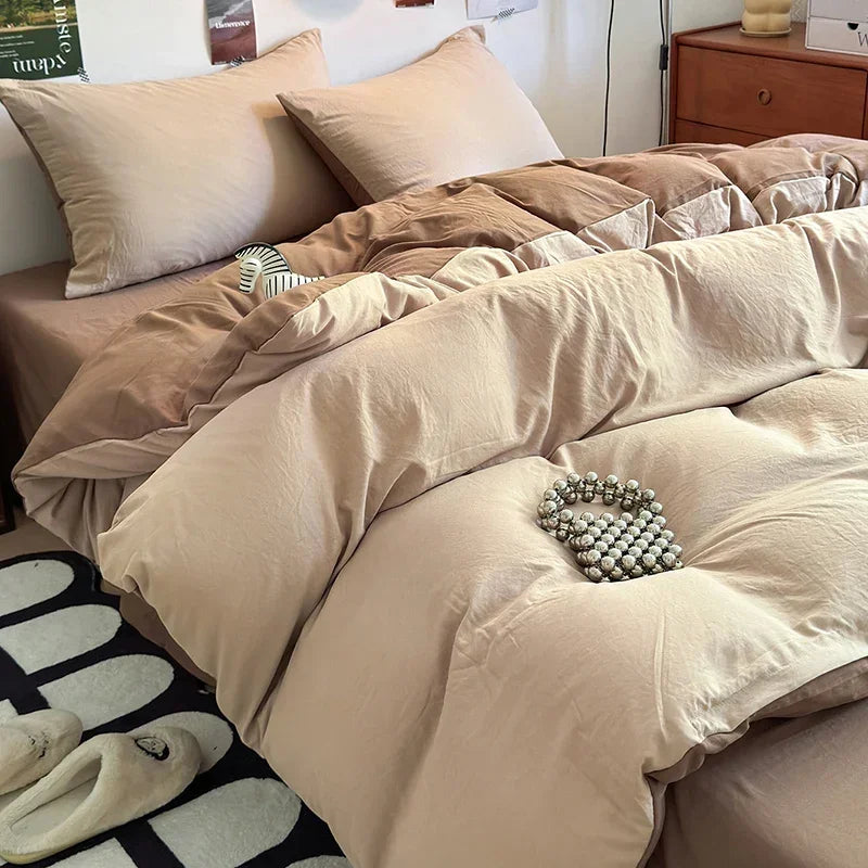 A beige duvet cover set with matching pillows and a folded towel on a bed.