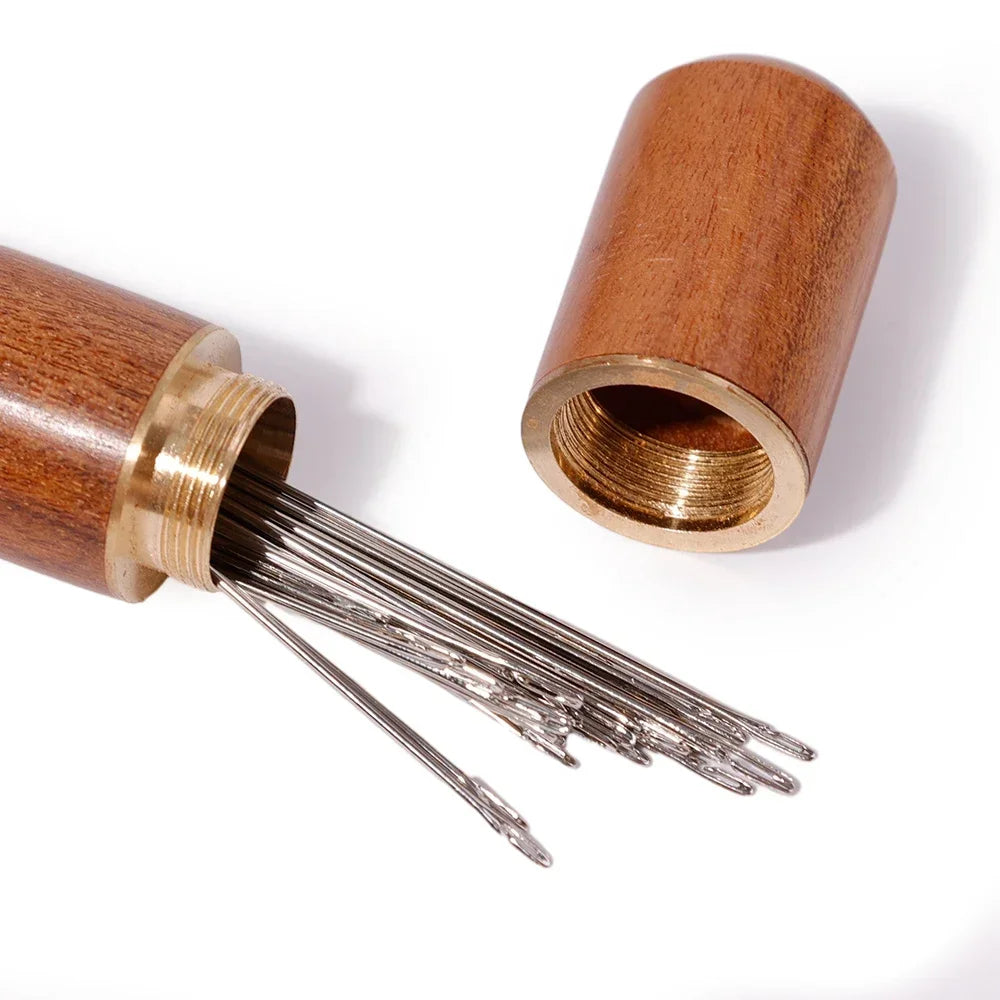 A set of self-threading sewing needles with a wooden storage cylinder.